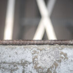 A close up photo of a screw fastening sitting on a block of concrete.